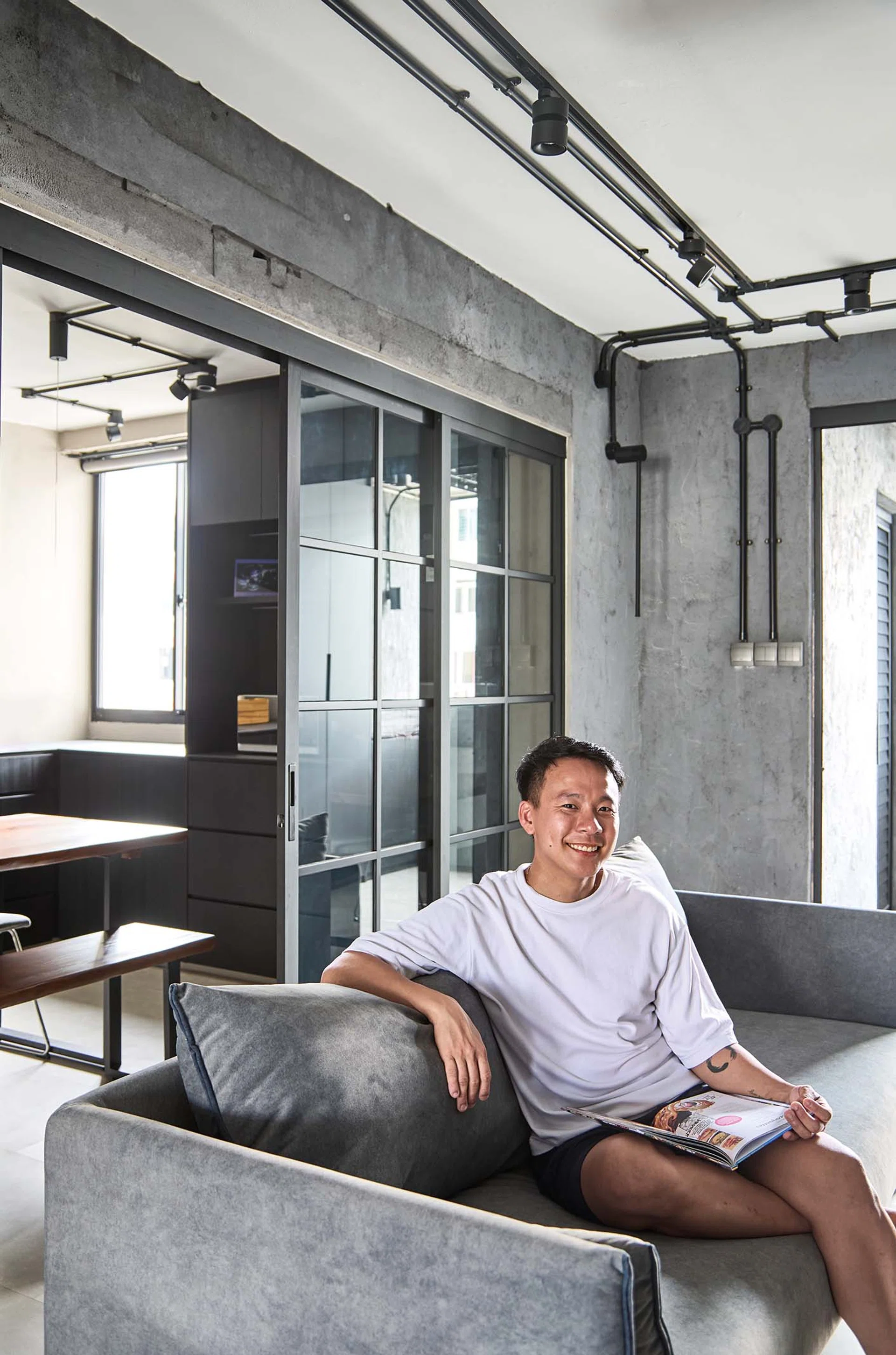 Kenny Shoo, a flight attendant in his mid-30s, poses for a picture on a sofa in his 646 sq ft 3-room HDB flat at Tampines Street 41.