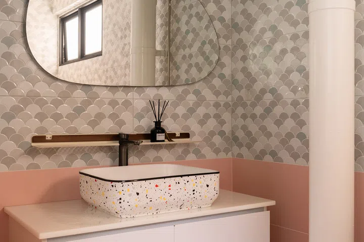 Scalloped tiles, pink walls and an irregular mirror brighten the bathroom at the end of the kitchen.