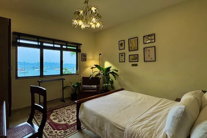 Wake up to idyllic coastal views: this first sea-view bedroom positions a queen bed directly facing the water, anchored by a floral chandelier and a vintage rug.