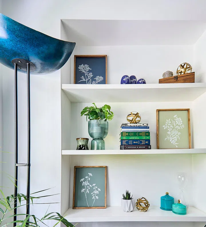 Home decorative items and framed memorabilia placed on a niche display shelf matches the cerulean blue tones of the room.