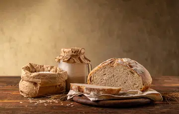 A rustic kitchen scene showcasing a freshly baked loaf of bread surrounded by essential ingredients.