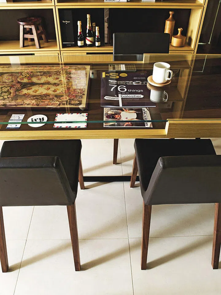 An empty area beneath the glass table top lets the homeowner display objects and collectibles. Interior design by Studio XMSL