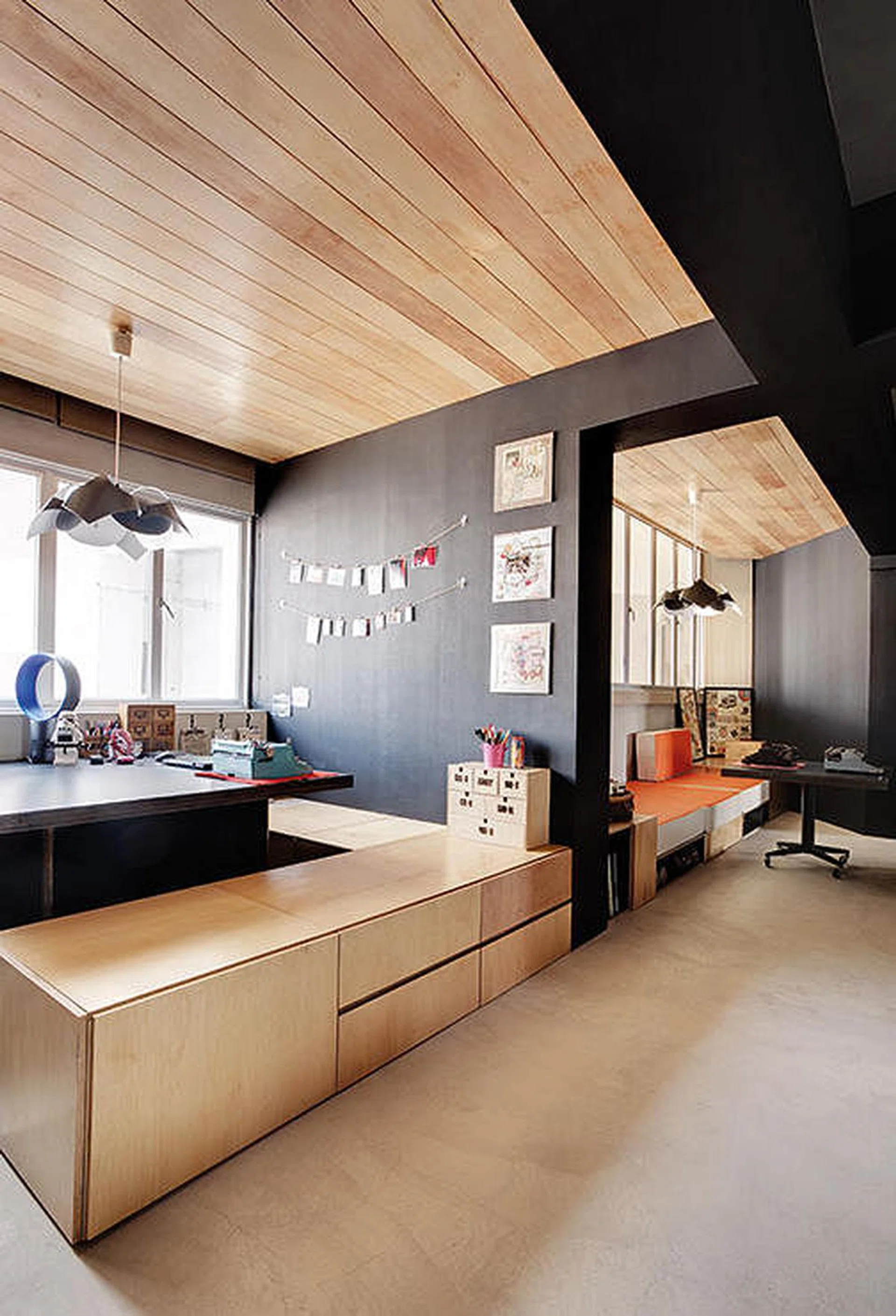 The designers set the study and lounging areas visually apart from the common area by covering the ceiling there with wooden planks and the walls in concrete screed.