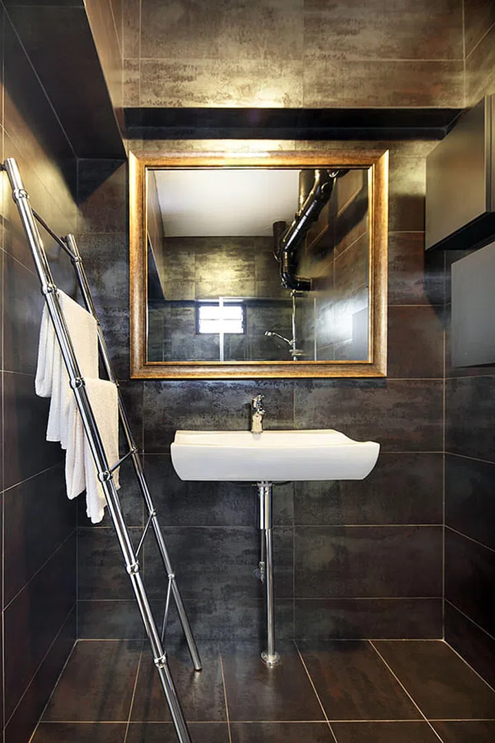 The mirror with gold trimmings works brilliantly to add emphasise against the darker bathroom tiles. Instead of the traditional wall mount hang rack, a 'steel ladder' was used to hang towels, clothes and whatnot.