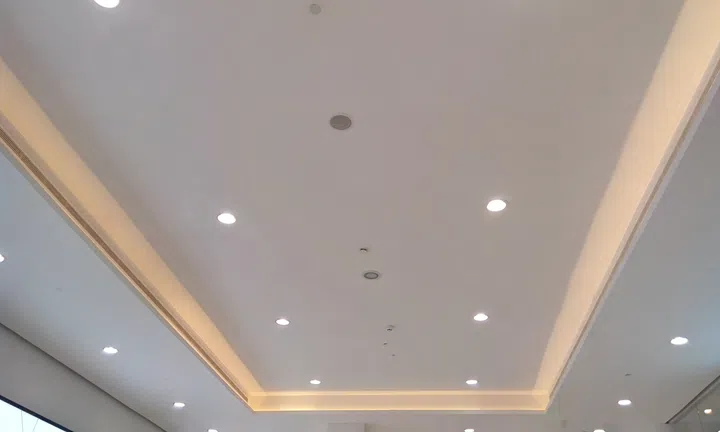 Gypsum false ceiling and cove finishes in a shopping mall interior finishes painted with White emulsion paint with decorative down lights to make beautiful ceiling view design