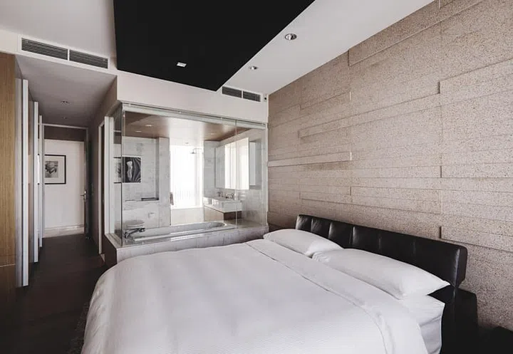 Echoing the living room aesthetics, the feature wall in the bedroom is dramatic without being imposing, and adds warmth to the space in this dark modern 4-bedroom condominium in Sentosa Cove.