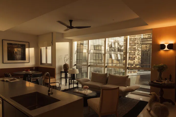 Evening light softens the space, where warm wood, steel, and neutral tones create a sense of quiet continuity.