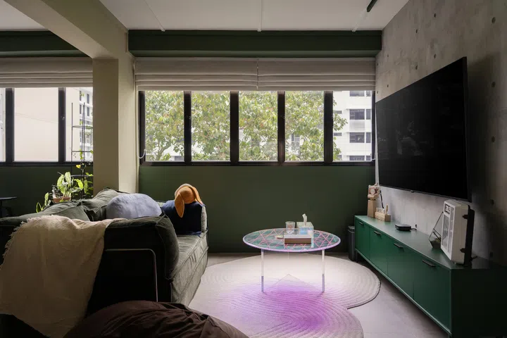 A kaleidoscopic glass table sits atop an irregular rug, injecting colour and a touch of whimsy into the living room.