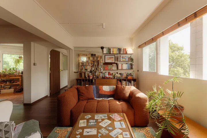 Collected rather than curated, the living room grows from a rust-hued sofa and bookshelves into a layered space shaped by Carousell finds, spontaneous purchases, and personal mementoes.