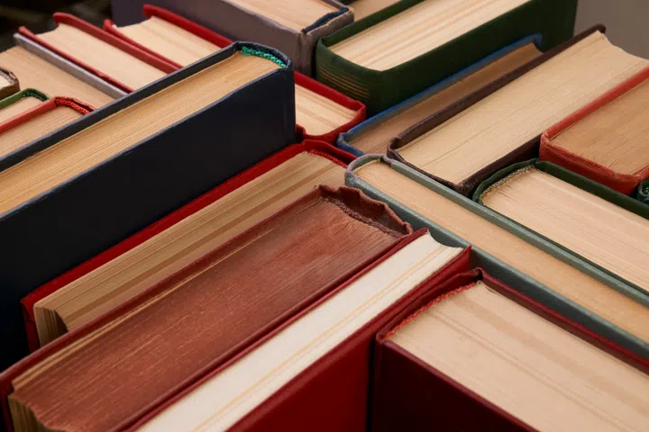 Stack of hardback books background. Many colorful books piles, close-up. Education concept