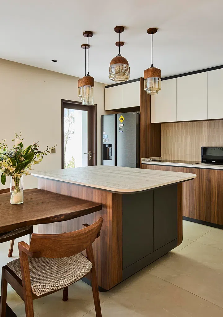 The cubic island forms a central working surface, paired with warm-toned pendants that add visual interest overhead.