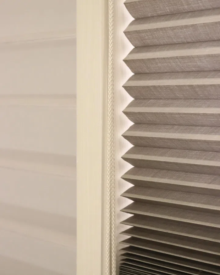 The pleated, cellular structure traps air within its pockets—an insulating layer that helps reduce heat transfer from the glass into the interior.