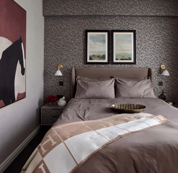 The bedroom’s dark, moody palette is balanced by sleek furnishings and layered textures.