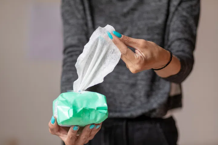 Old woman hand with turquoise nails taking the wet wipe to clean skin or surface stock photo.