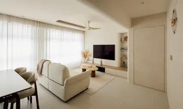 Sheer curtains wash the living room in soft daylight, giving the space its signature calm.