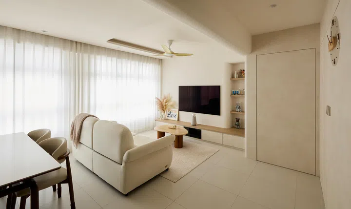 Sheer curtains wash the living room in soft daylight, giving the space its signature calm.