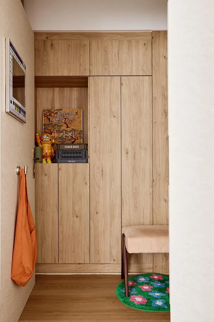 Full-height storage lines the foyer, keeping shoes and bags tucked away while maintaining the warm wood tone that defines this decompression space at the entrance.