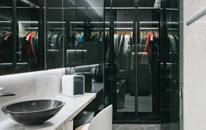 A vanity area with large mirrors in front of a dark walk in closet
