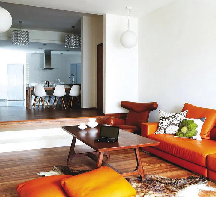 The orange leather sofa from Air adds colour to the wood-hued interiors. Rug and coffee table, from Lorgan’s The Retro Store; Vases, from The Touch; Cushions, from Friven & Co.