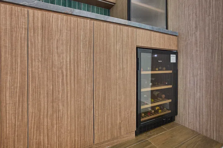 A built-in wine fridge is tucked seamlessly below the counter, maintaining the clean, continuous lines of the cabinetry.