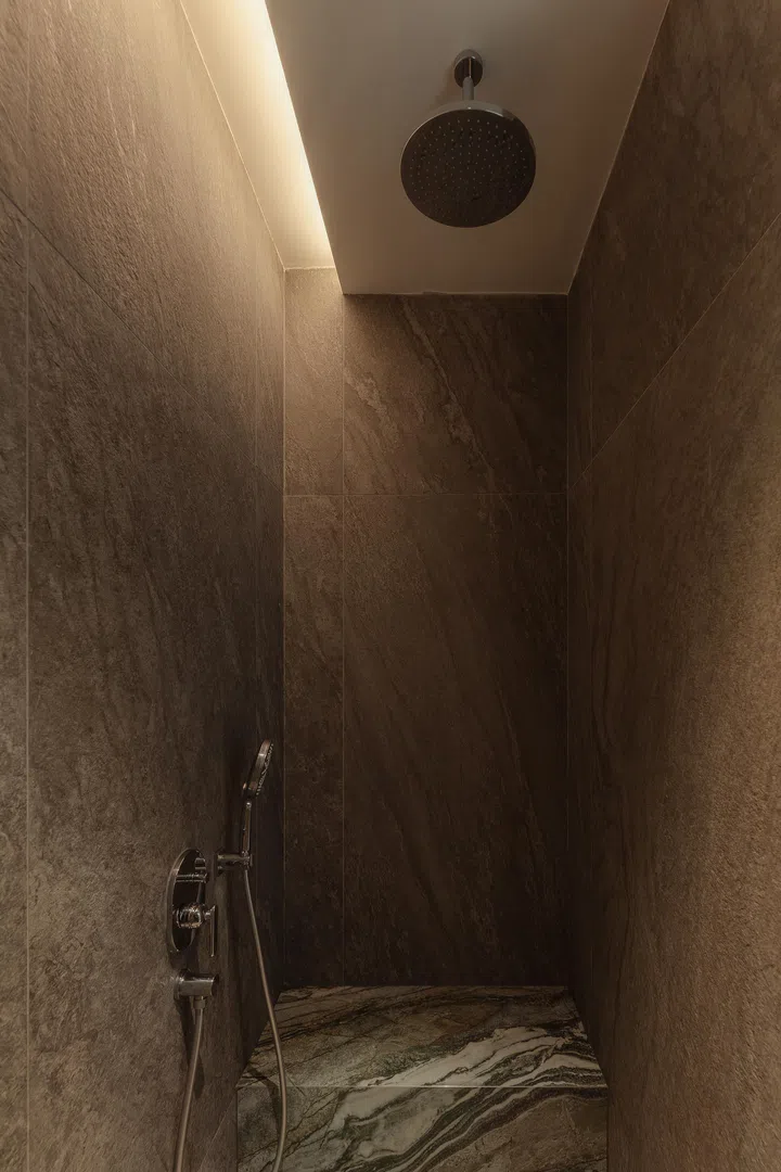 The walk-in shower combines textured stone and concealed lighting for a serene, spa-like feel.