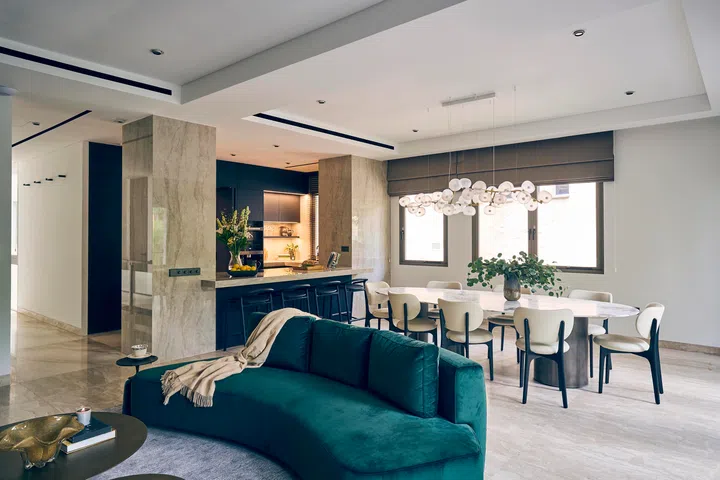 Curved furnishings and a sculptural chandelier soften the open-plan living, dining, and kitchen area.