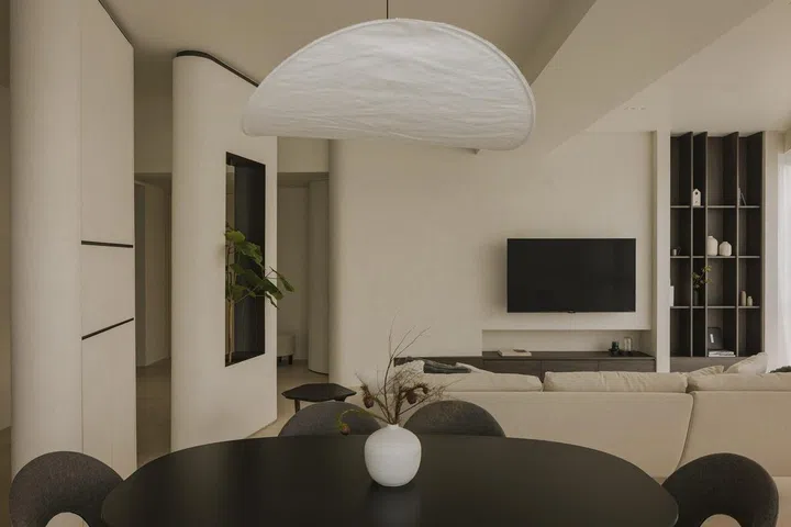 Dining table overlooks the living room and television in this all black and white private condominium apartment in Serangoon Gardens.