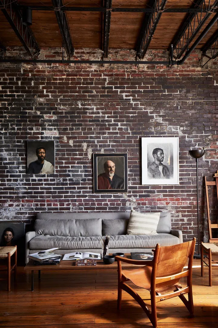 Young artist William Rushton's living room with exposed brick walls and ceiling beams. Credit: Brie Williams