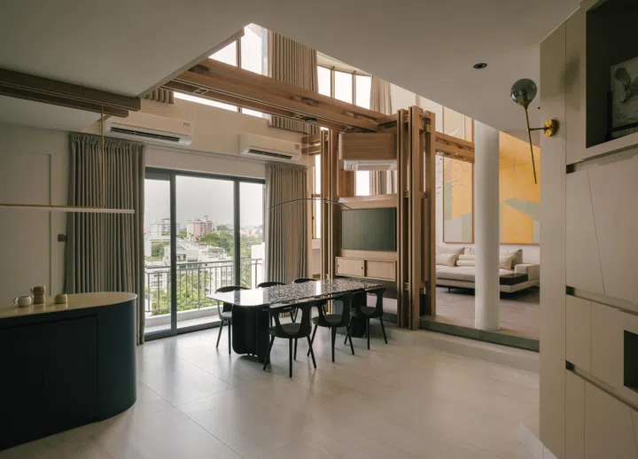 The timber axis defines the open-plan layout, framing the dining area while maintaining visual continuity across levels.