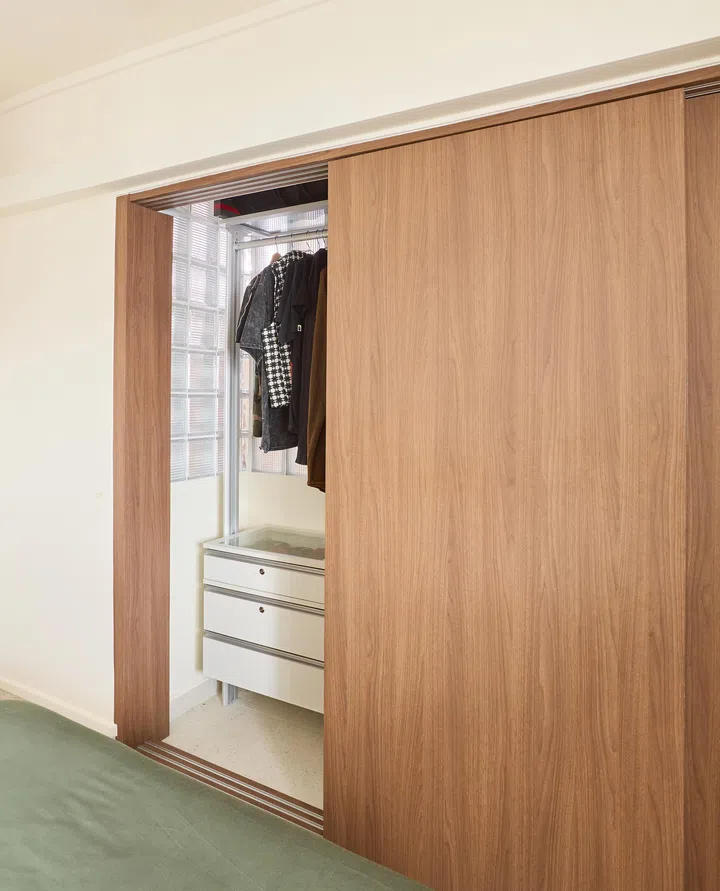 Stanley converted part of the kitchen into a wardrobe, separated by sliding wood panels and the glass brick wall that diffuses natural light.