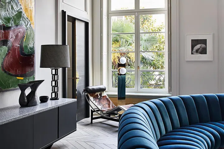 A Le Corbusier recliner creates an inviting corner by the tall windows.