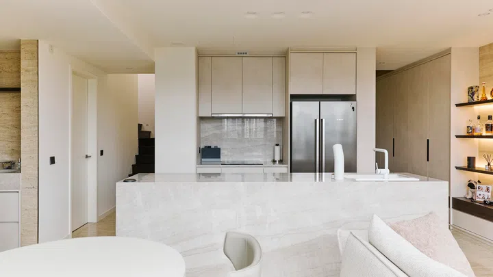 A travertine-topped island anchors the open-concept dry kitchen, creating a sculptural yet functional centrepiece for gatherings and everyday cooking.