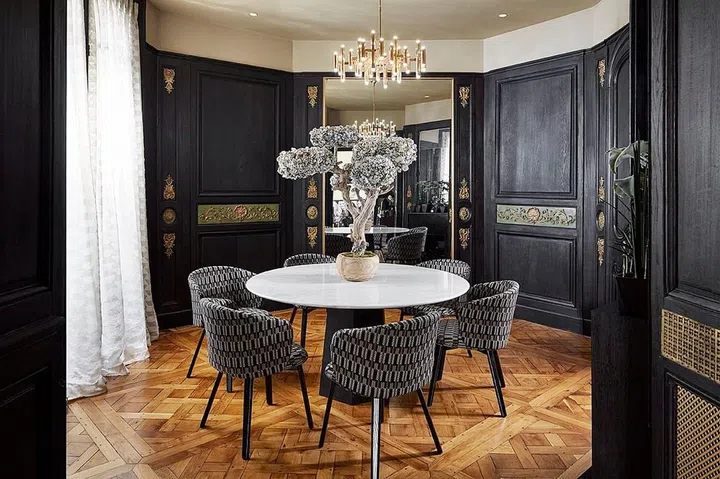 Black wainscoting walls for a classy dining room with herringbone wooden flooring.
