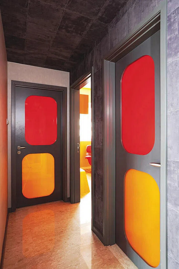 These bright doors bring life to the dull grey corridor of this home.