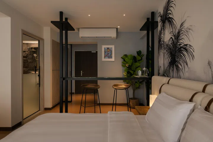 The reconfigured layout merges the bedroom and living zones, creating one continuous, open-plan suite space flanked by a glass bar counter.