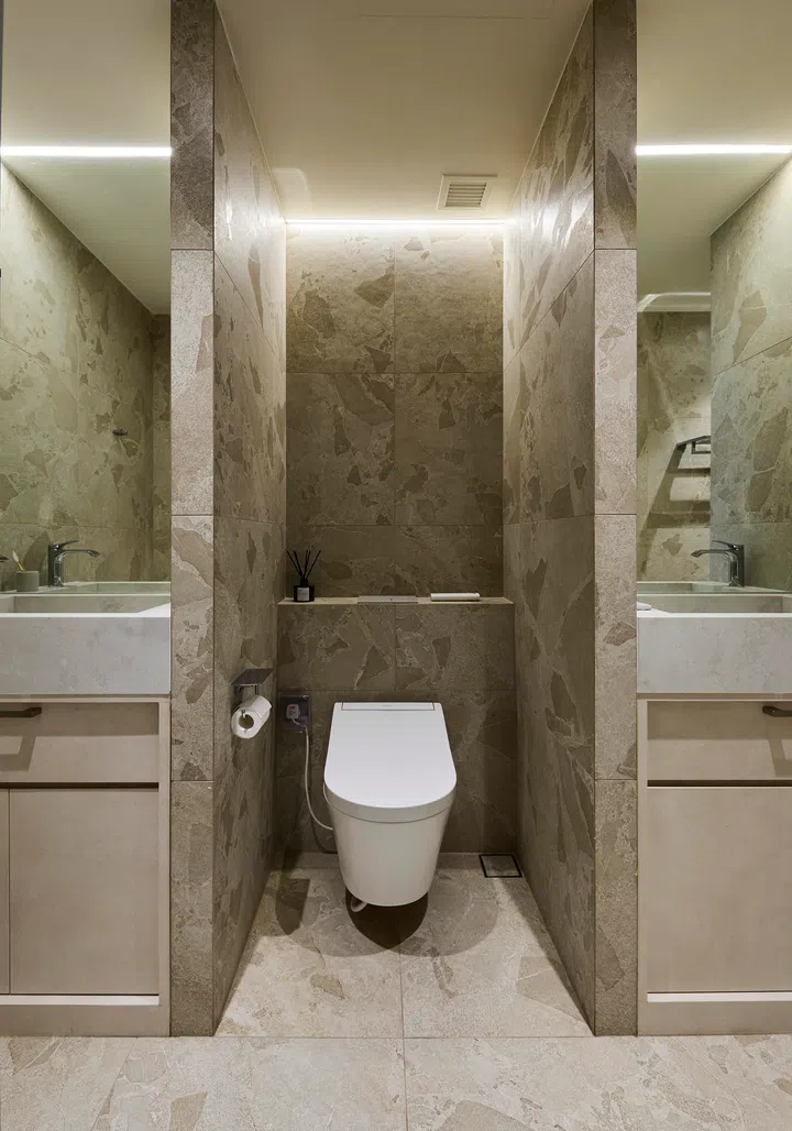 The reconfigured common bathroom balances space efficiency with natural materials, with a stone vanity harmonising with the kitchen island.