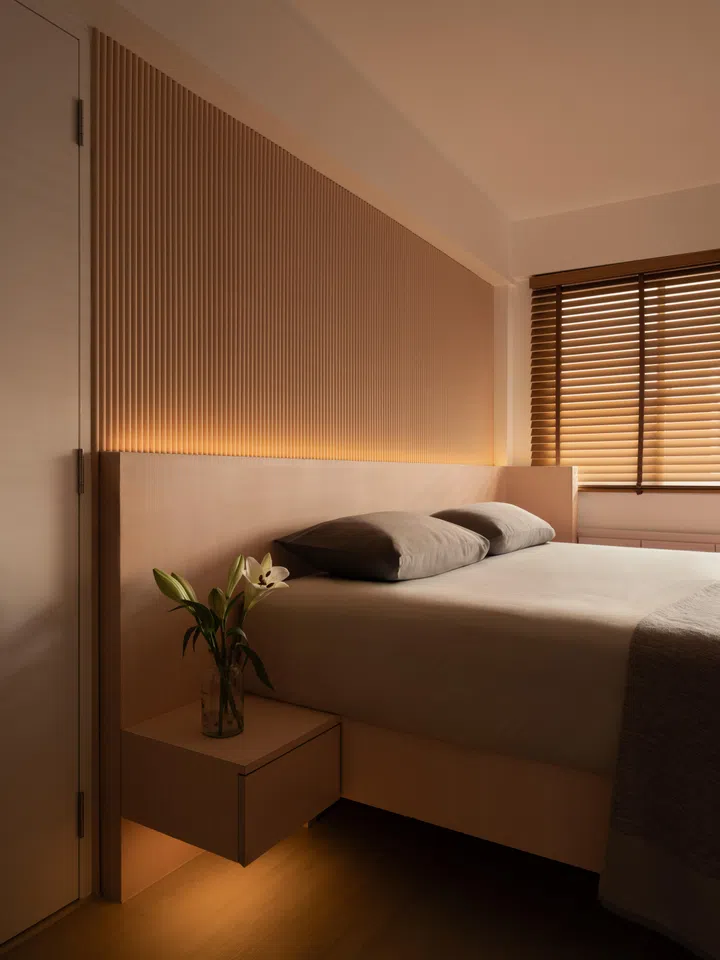 Fluted timber panels form a continuous bedhead wall, softly backlit to introduce depth without the need for artwork or overhead fixtures.