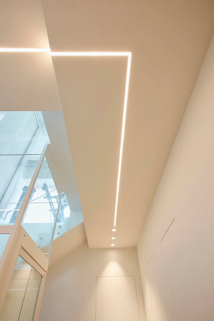 Linear recessed lighting follows the direction of movement, reinforcing a clean and controlled flow.