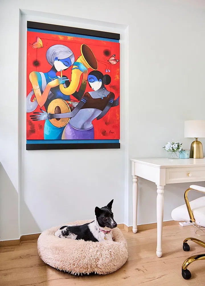 An abstract portrait of a musician playing the sitar (painted in shades of blue, no less) is framed on the wall, above her pet dog's bed.