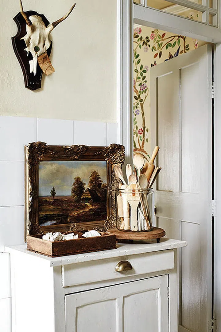 A single freestanding white kitchen cabinet with wainscoting cabinet doors. Keep your utensils in one big glass jar. We love the rustic look of this one! Interior Design by Belouk