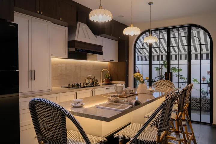 A marble-finish island doubles as a dining table, illuminated by charming pendant lamps.