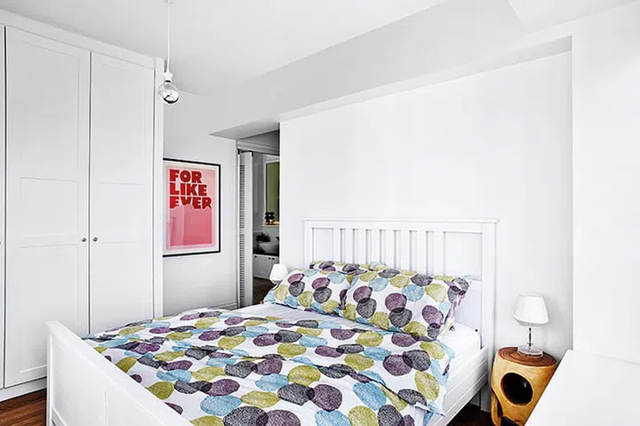 Interior designer, JQ, doubled the wardrobe space with an L-shaped unit and paired the simple bed with a pair of wooden stools repurposed as bedside tables.