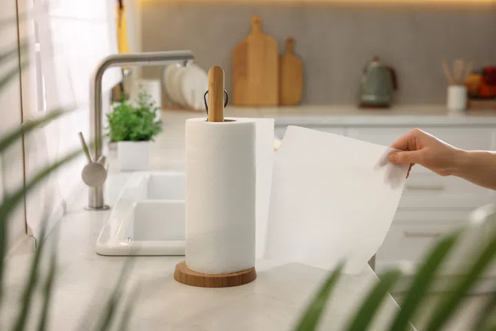 Woman using paper towels in kitchen, closeup.