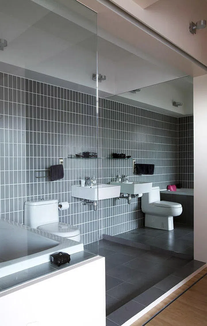 Grey tile bathroom with glass panel door. Interior Design: Spacedge Designs