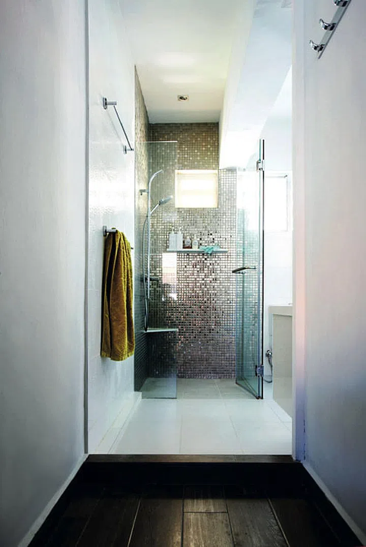 Silver mosaic tiles reflect the light from the small ventilation window in the bathroom, creating a bright and airy effect.