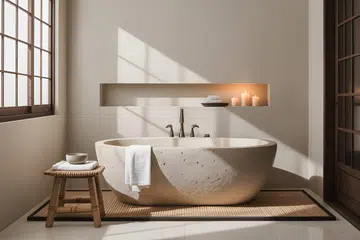 A tranquil bathroom features a stone-like freestanding tub bathed in soft natural light.