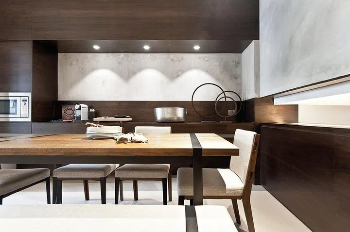Refined walnut veneer makes a big statement when paired with bare concrete in the dining room, which features a dining set from Commune Home.