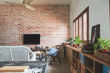 Living room with exposed red brick wall in a Mediterranean-style 3-bedroom walk-up in Tiong Bahru