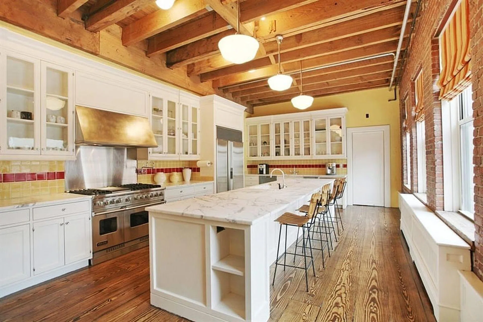 Wide plank wood floors, marble countertops, and new stainless steel appliances make this beautiful urban all-white farmhouse-style kitchen in Taylor Swift's penthouse in New York. Photo by Celebrity Homes
