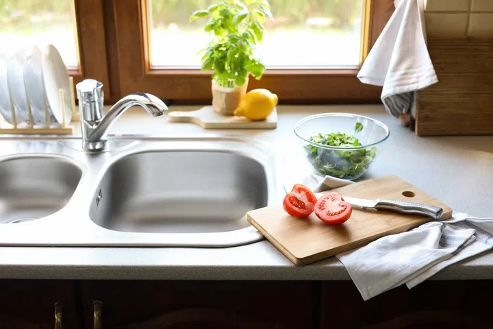 Cut tomato and knife near sink in kitchen.